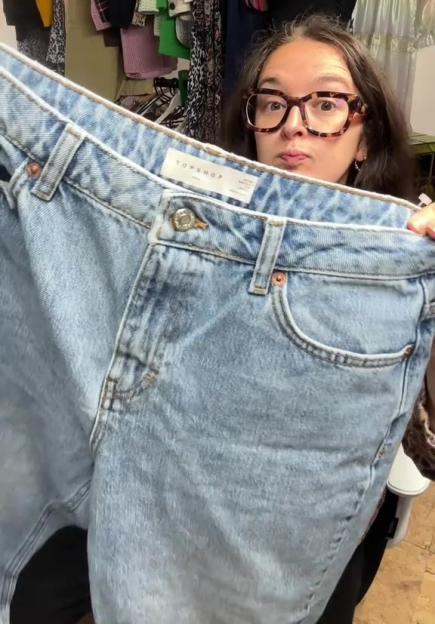 Woman holding up a pair of Topshop jeans.