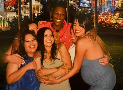 A man with five wives embraces them in a group photo.