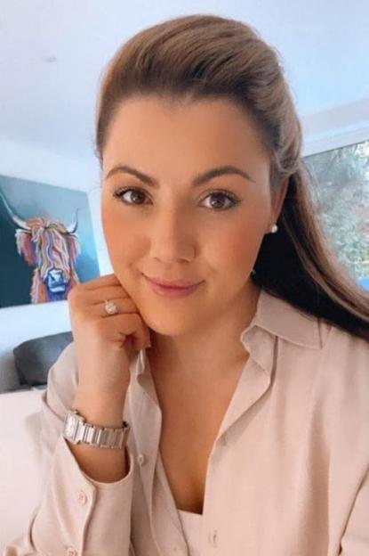 Woman in beige shirt with engagement ring and watch.