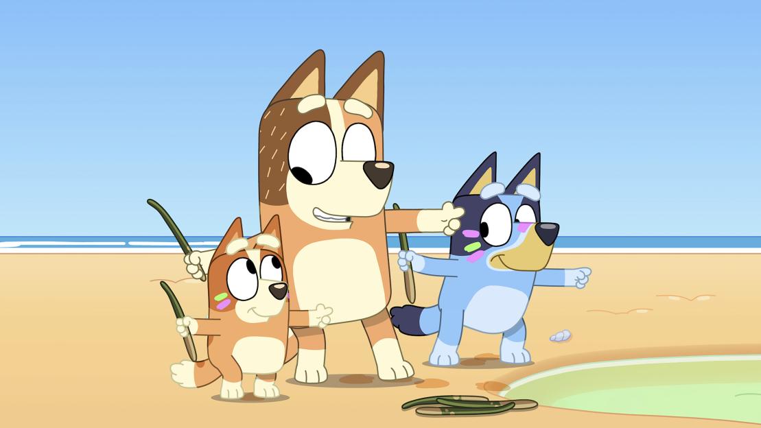 Illustration of three dogs on a beach holding sticks.
