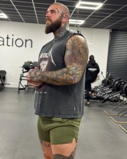 Tattooed man in olive green shorts at the gym.