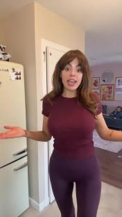 Woman in maroon top and purple leggings in a kitchen.