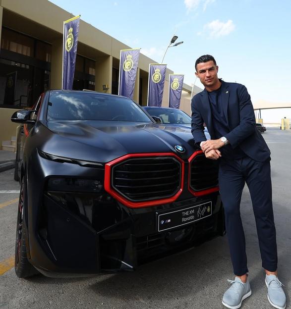 Cristiano Ronaldo poses next to a new black BMW, gifted by Al-Nassr.