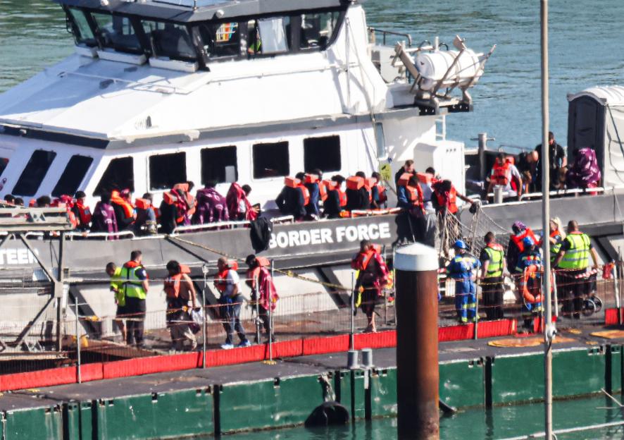 Migrants wearing life jackets arriving at a port on a Border Force boat.