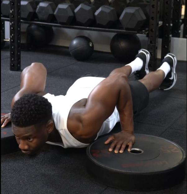 Man doing push-ups with hands on weights.