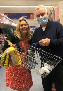 Two people shopping in a store, holding shopping baskets.