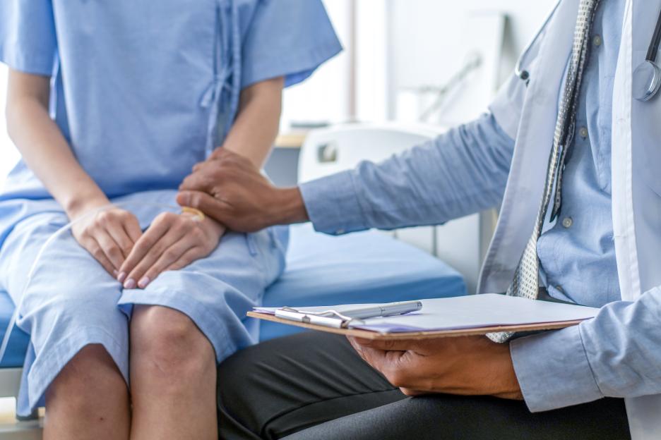 Doctor holding a patient's hand and reviewing notes.