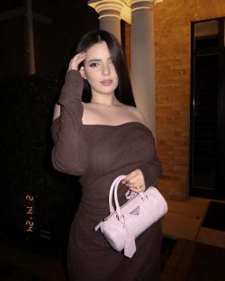 Woman in brown dress holding a pink handbag.