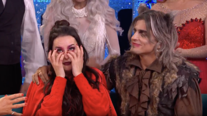 Amber Davies cries with hands covering her eyes, next to a man dressed in a brown furry costume.
