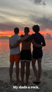 Three brothers standing on a beach at sunset. 