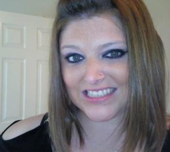 Woman with shoulder-length brown hair and a nose piercing.