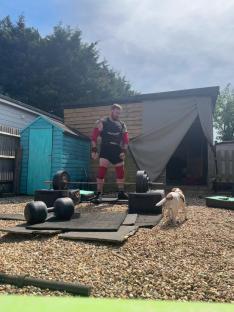 Strongman preparing to lift weights in his backyard.