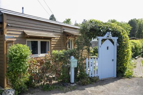 Small wooden house with a light blue gate and mailbox.