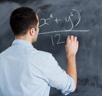 Man writing math equation on chalkboard.