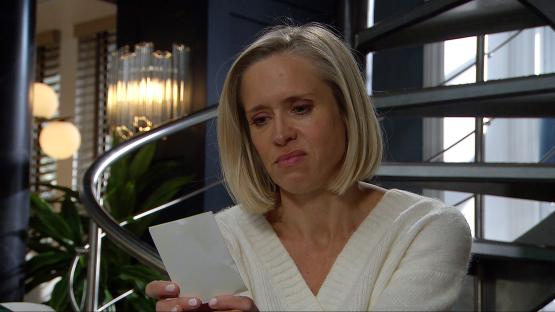 A woman looks at a photograph with a troubled expression.
