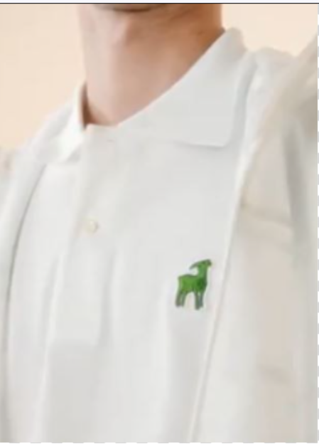 Close-up of a white polo shirt with a green goat logo.