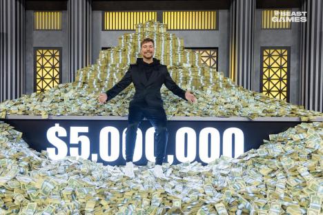 Man sitting on a large pile of money; $5,000,000 displayed.