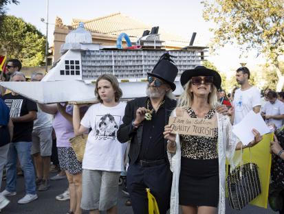 Protestors carry a cardboard cruise ship model and a sign advocating for quality tourism.