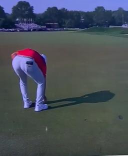 Golfer bending over on the green.