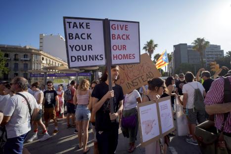 Anti-tourism protestors in Palma holding signs that read "Take Back Your Drunks" and "Give Back Our Homes".