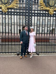Couple standing in front of Buckingham Palace gates.