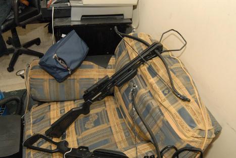 a crossbow is sitting on a couch next to a blue bag