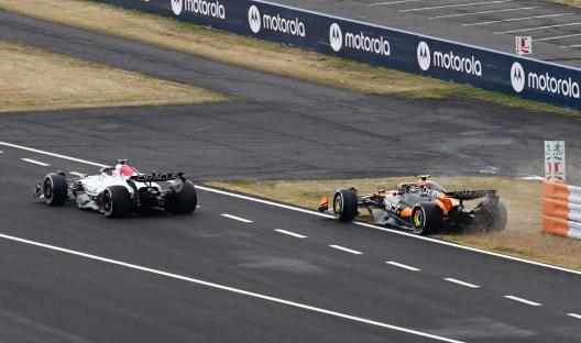 Formula 1 race cars on a track, one car is off the track.