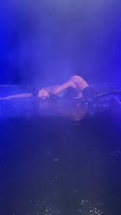 Woman in dark clothing lying in water.