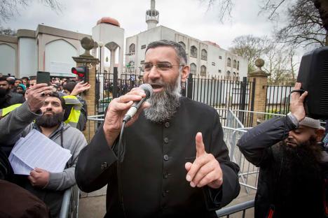 Anjem Choudary speaking into a microphone outside a mosque, urging Muslims to abstain from voting.
