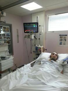Patient in hospital bed with medical equipment.