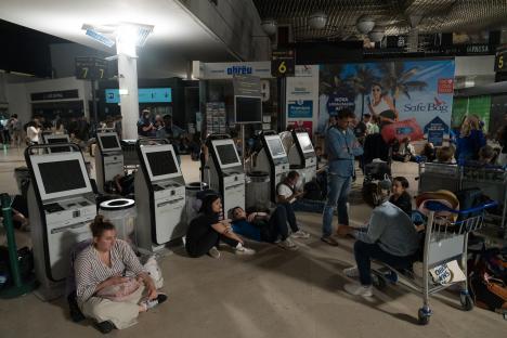 Passengers sitting on the floor of an airport during a power outage.