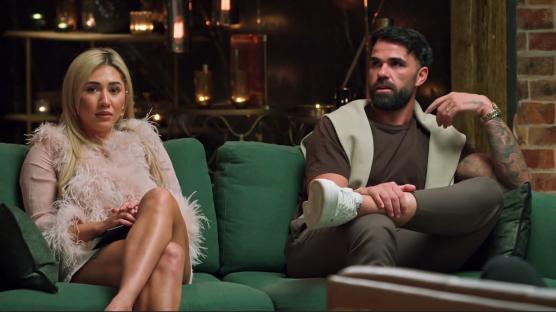 A Married at First Sight Australia couple sits on a couch.
