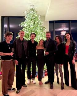The Beckham family and their children posing for a Christmas photo in front of a decorated tree.