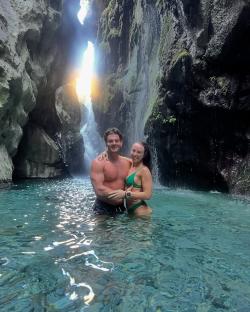 Couple embracing in a waterfall pool.