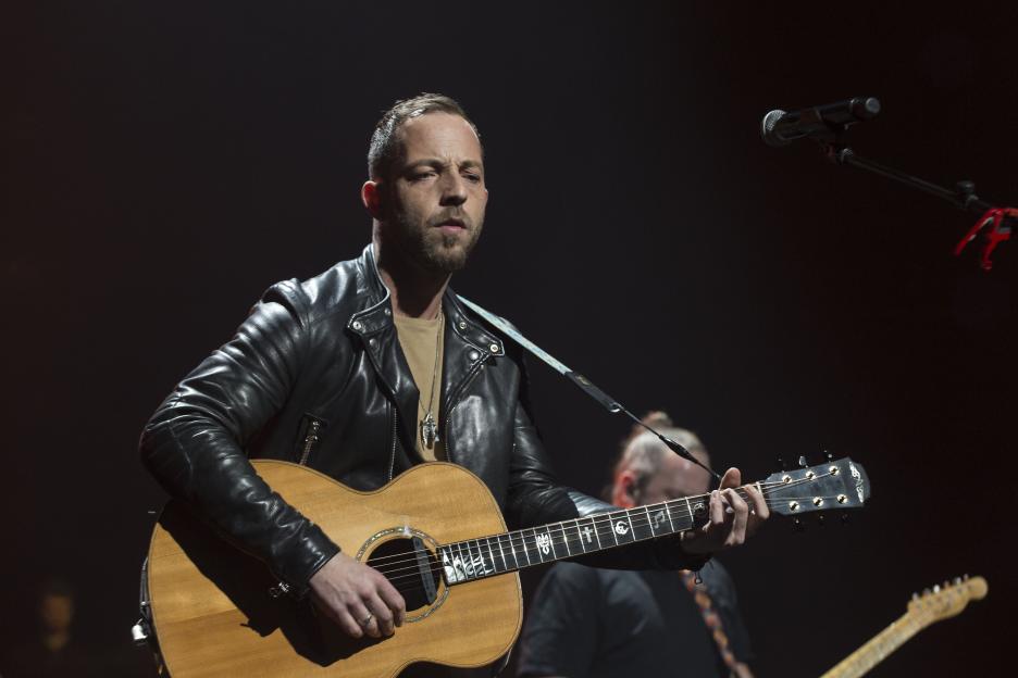 James Morrison playing an acoustic guitar on stage during a performance.
