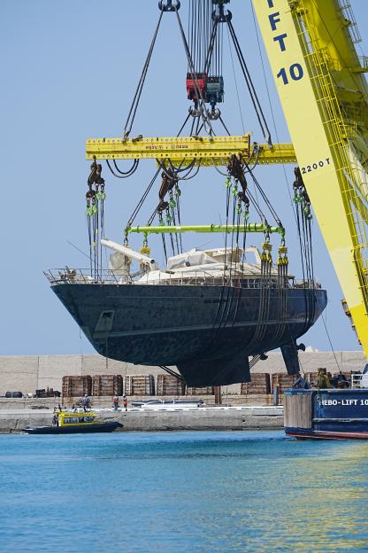 A crane lifts a sunken superyacht from the water.