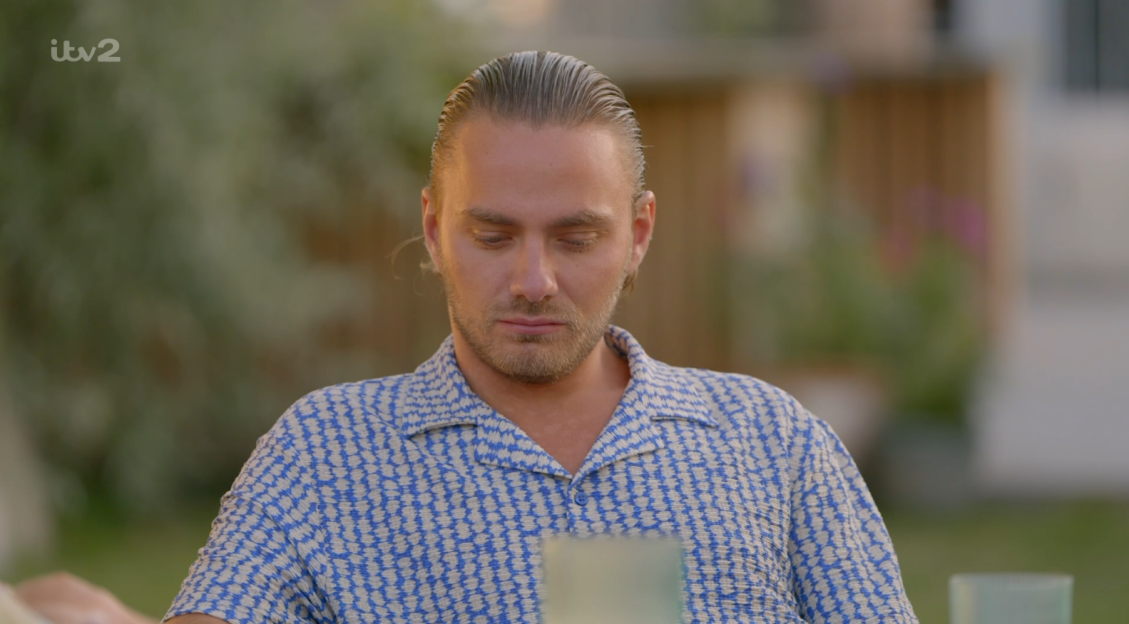 Man looking down in a patterned shirt.