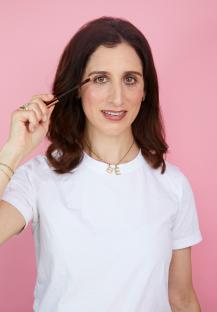 Woman applying brown mascara.