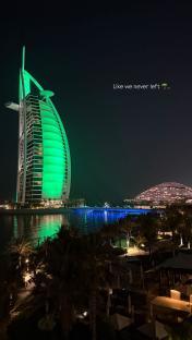 Night view of the Burj Al Arab Jumeirah in Dubai, lit in green.