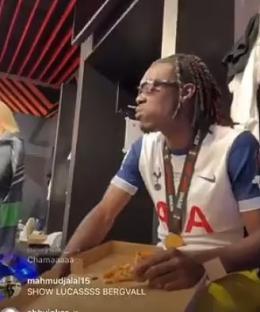A Tottenham Hotspur player eating pizza in the locker room.