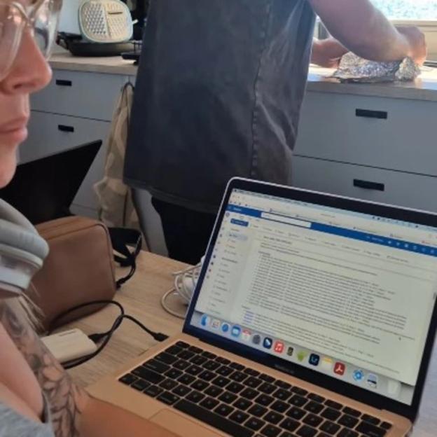 Person working on laptop in kitchen.