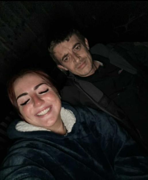 A man and woman posing for a selfie in low light.