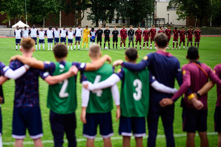 Soccer teams standing on the field for the national anthem.