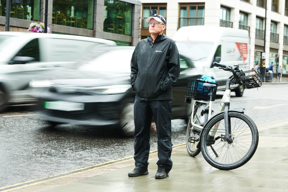 Man standing by his bicycle on a city street.