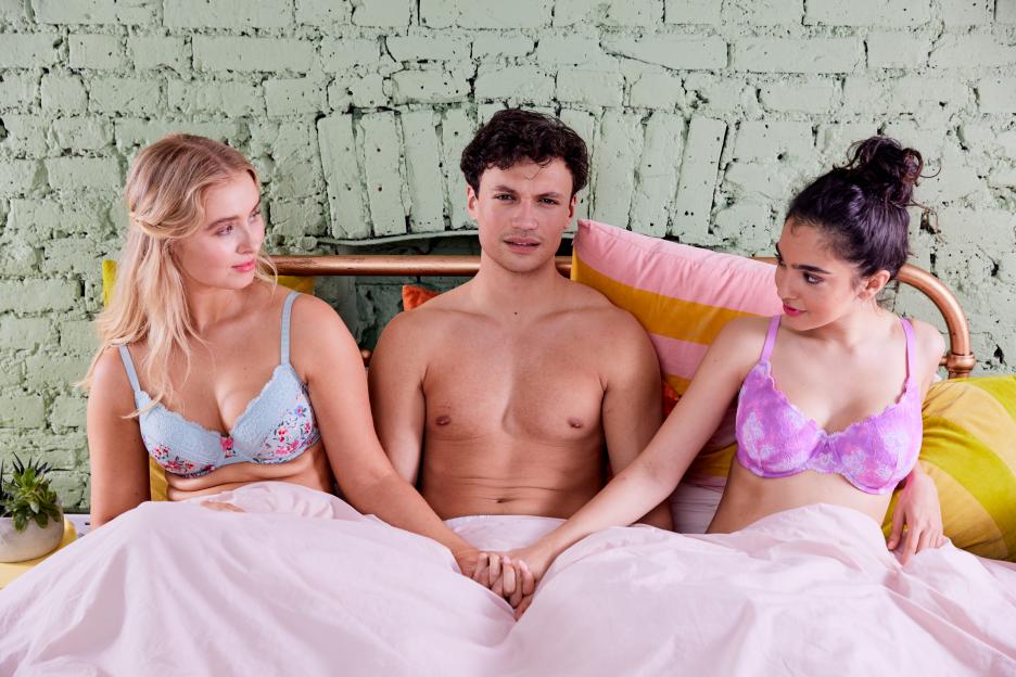 Man sitting in bed holding hands with two women.