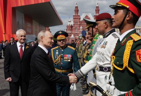 Vladimir Putin shaking hands with a serviceman at a military parade.