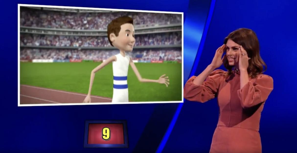 A woman in a rust-colored dress looking at a screen with an illustration of a male runner, set against a stadium background.