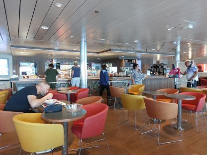 Passengers eating and waiting for food in a ship's cafeteria.