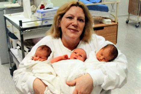 Woman holding her newborn triplets.