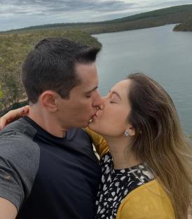 A couple kissing overlooking a lake.